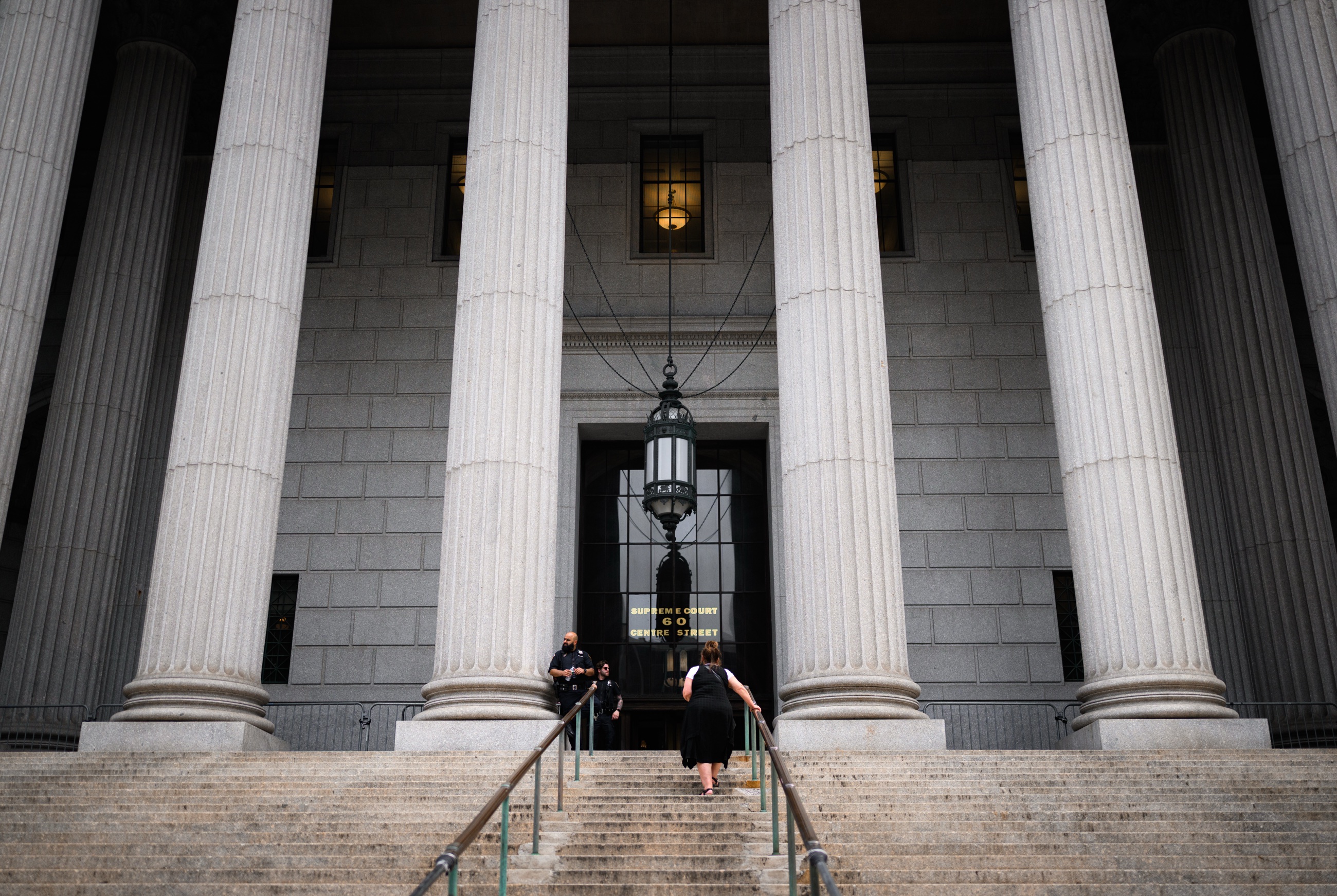 A woman climbing the broad courthouse steps beneath stone columns