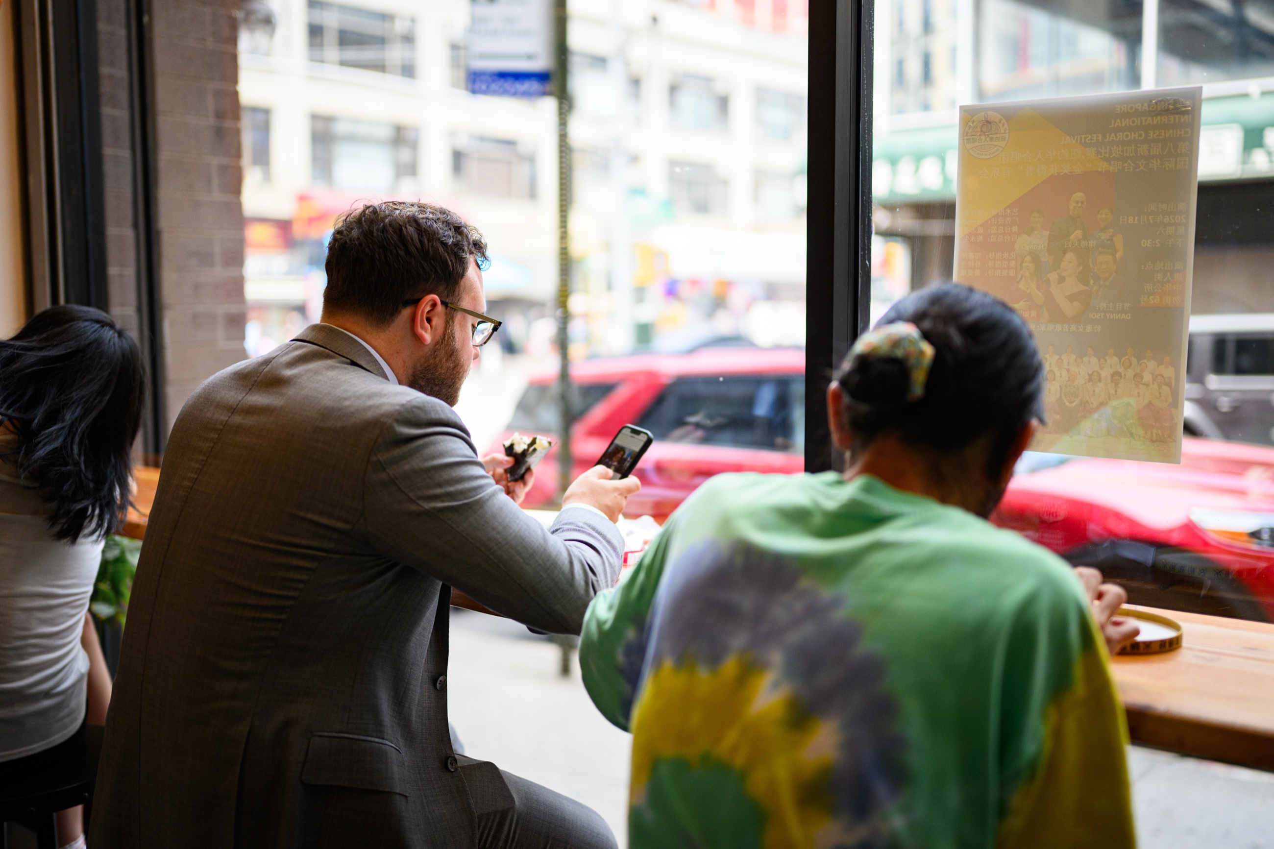 A man in a suit pausing for lunch beside a local customer in Chinatown