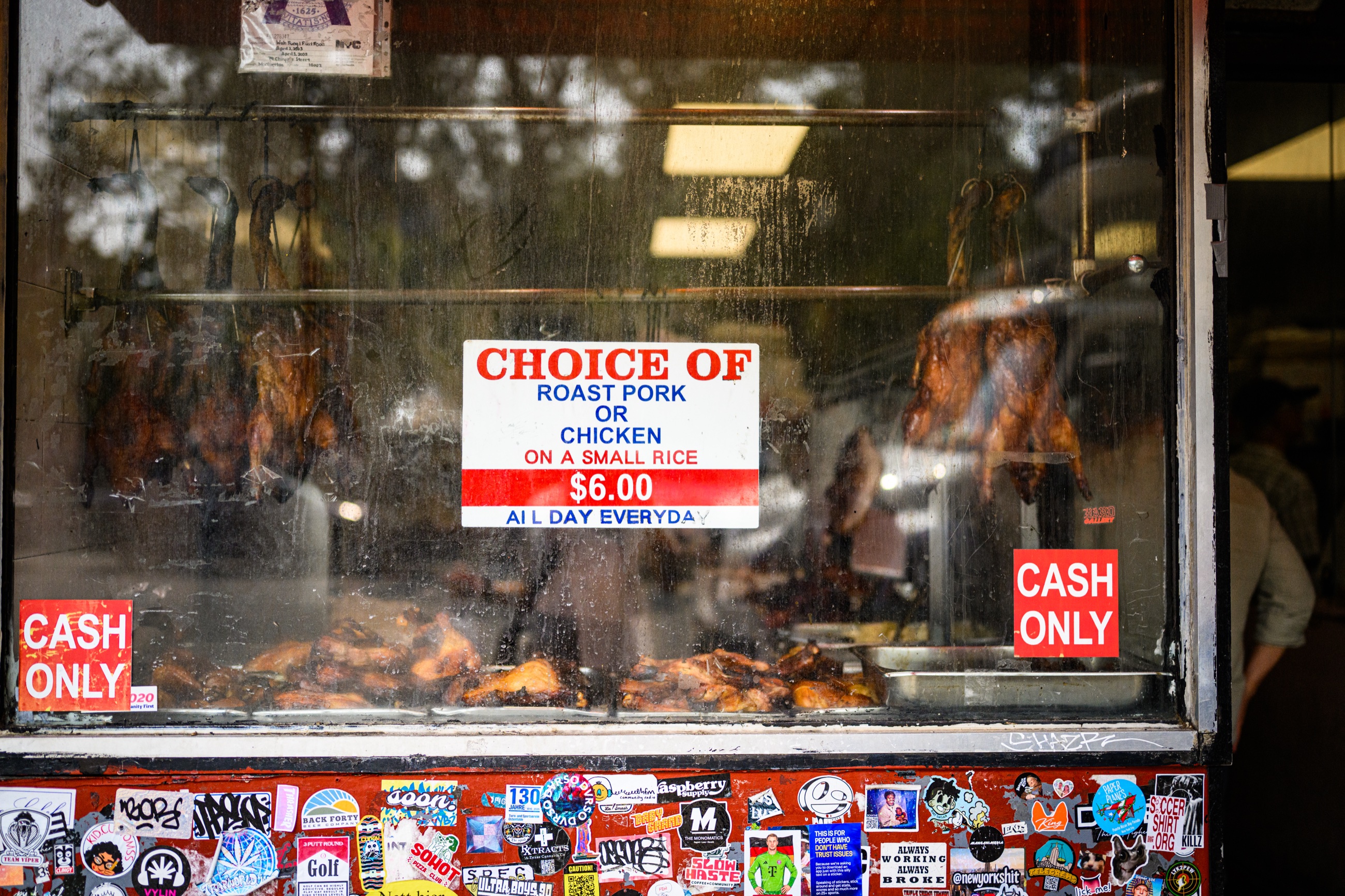 Roasted pork and chicken behind a weathered storefront window