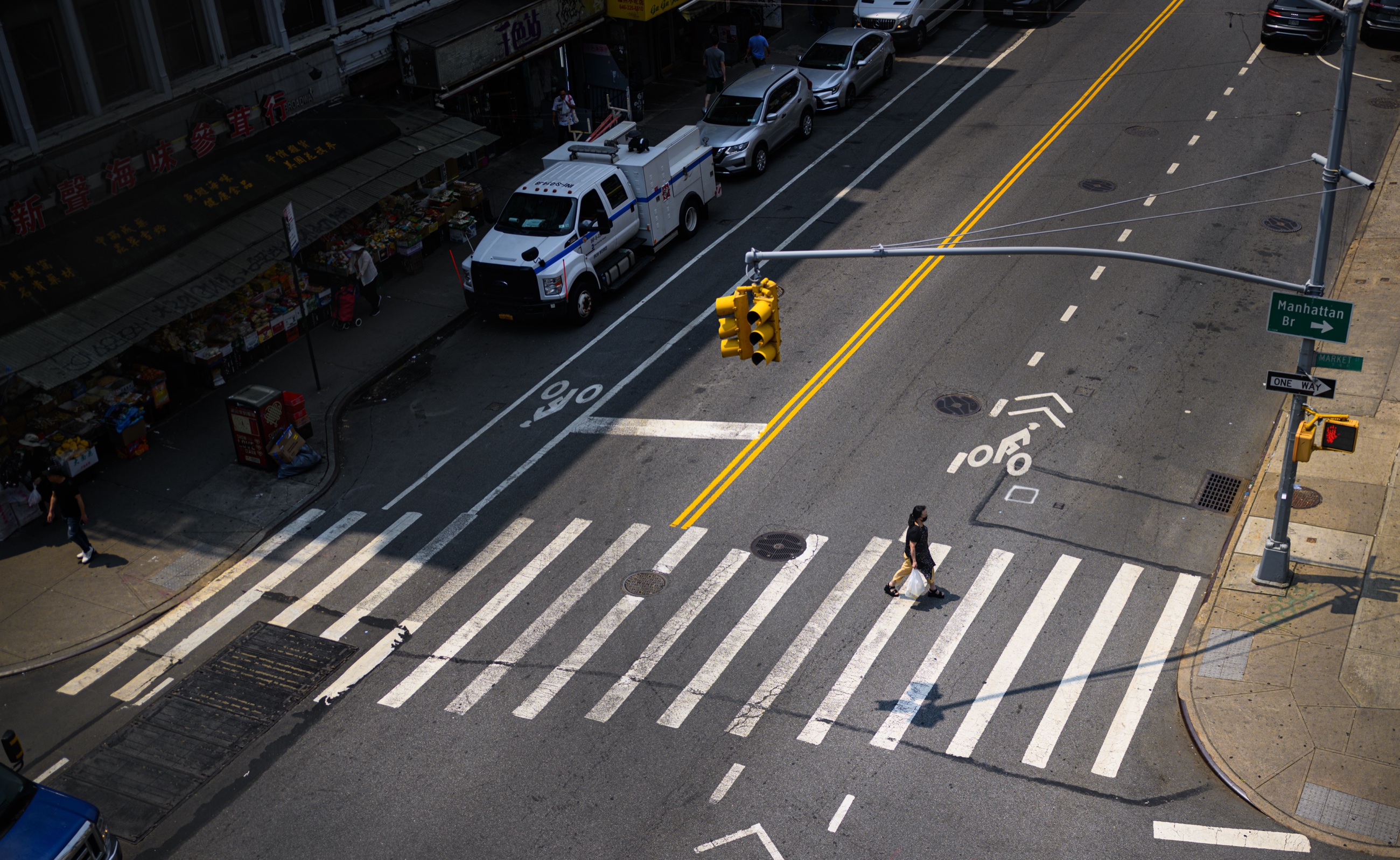 A woman crossing Market Street beneath the Manhattan Bridge
