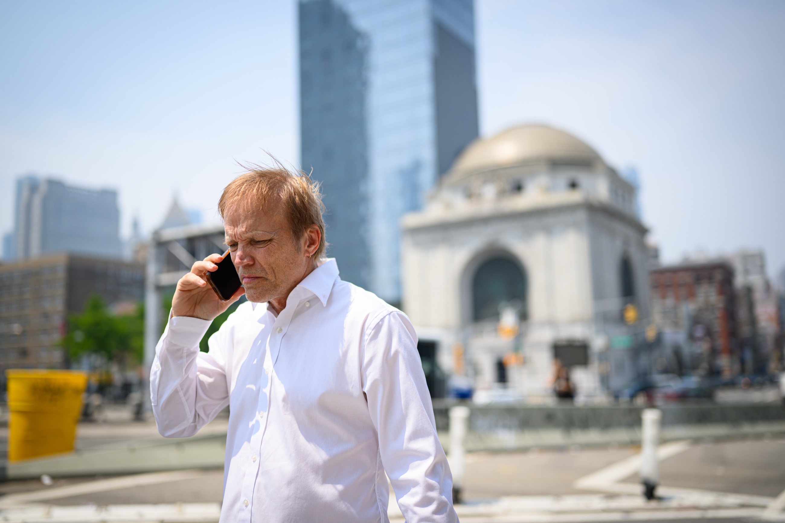 A man on the phone with the courthouse district behind him