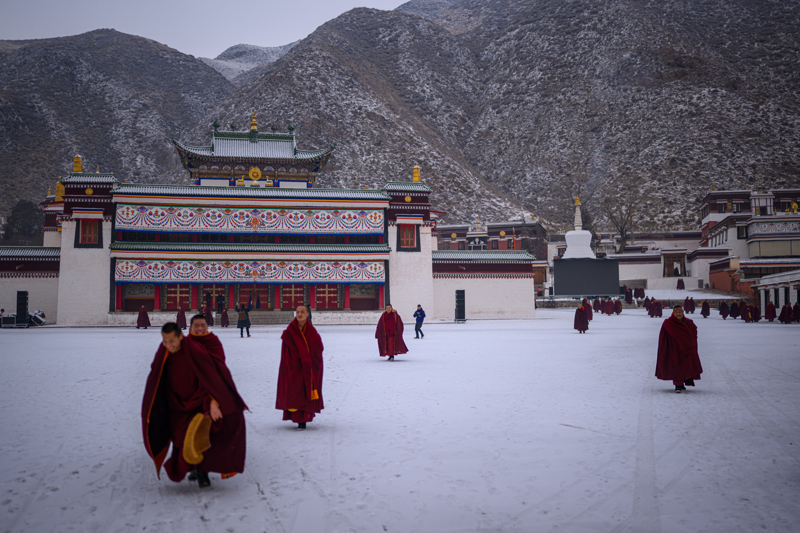 Monks walking through a snow-covered monastery courtyard