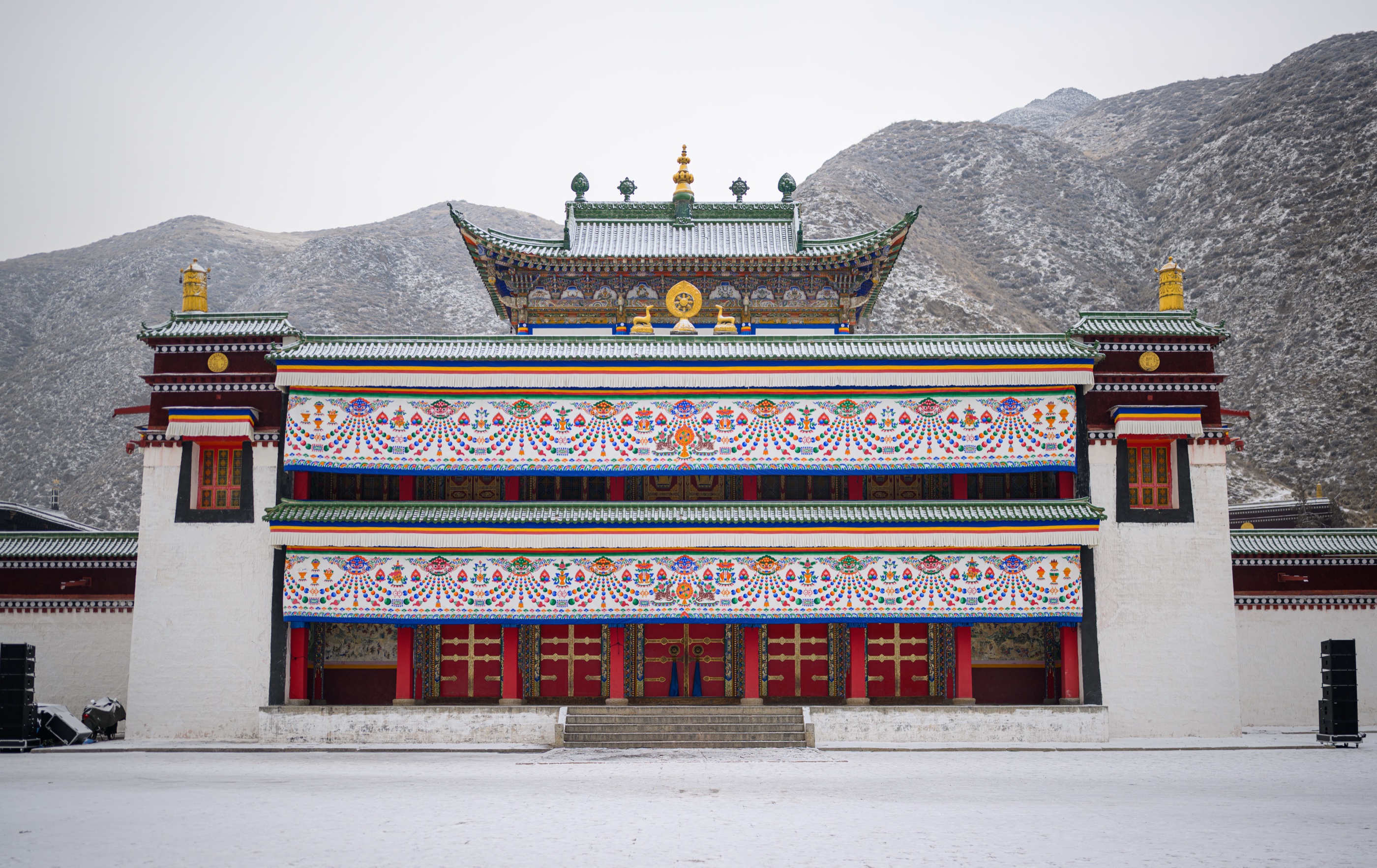 A painted monastery building below snow-dusted mountains