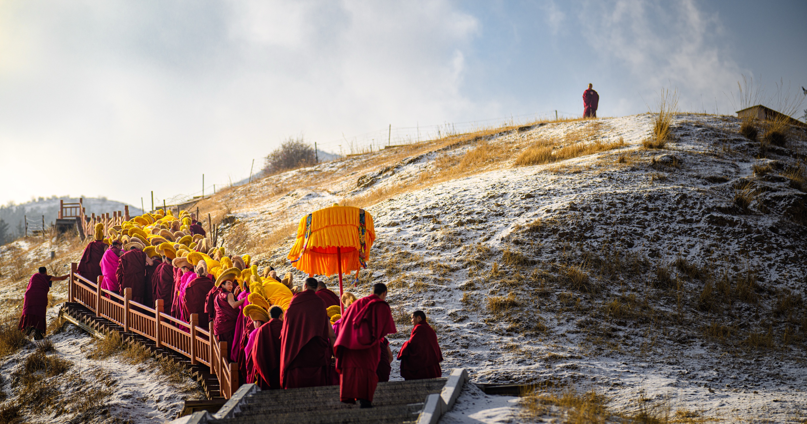 Monks ascending a wooden walkway on the hillside