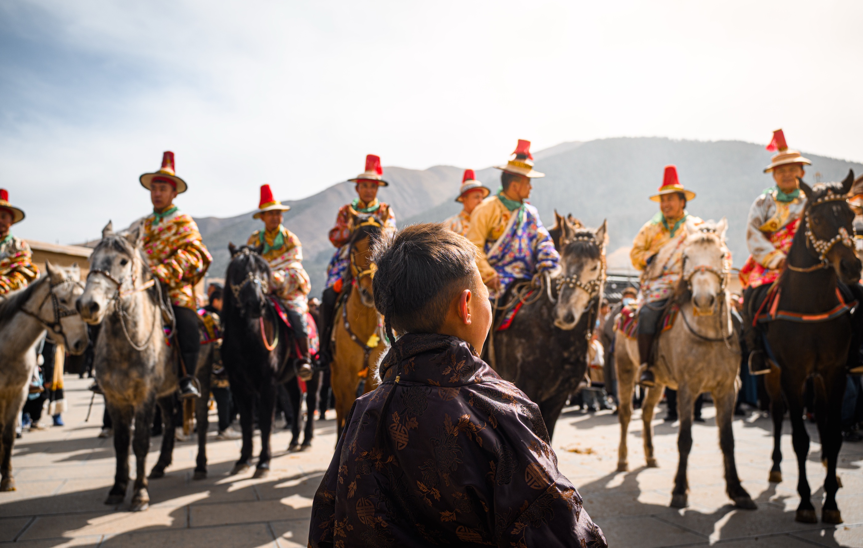 Mounted riders crossing the open ground outside the monastery