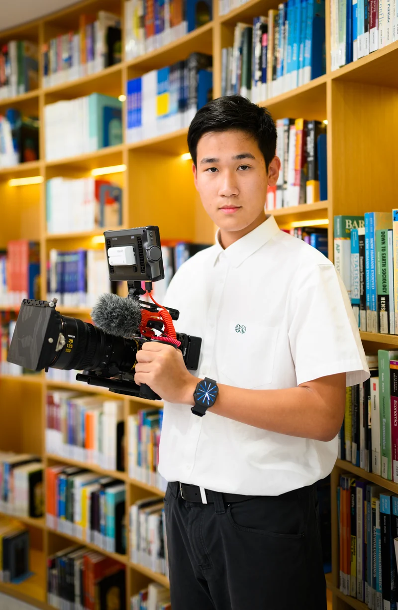 Daniel Feng holding a camera in a library