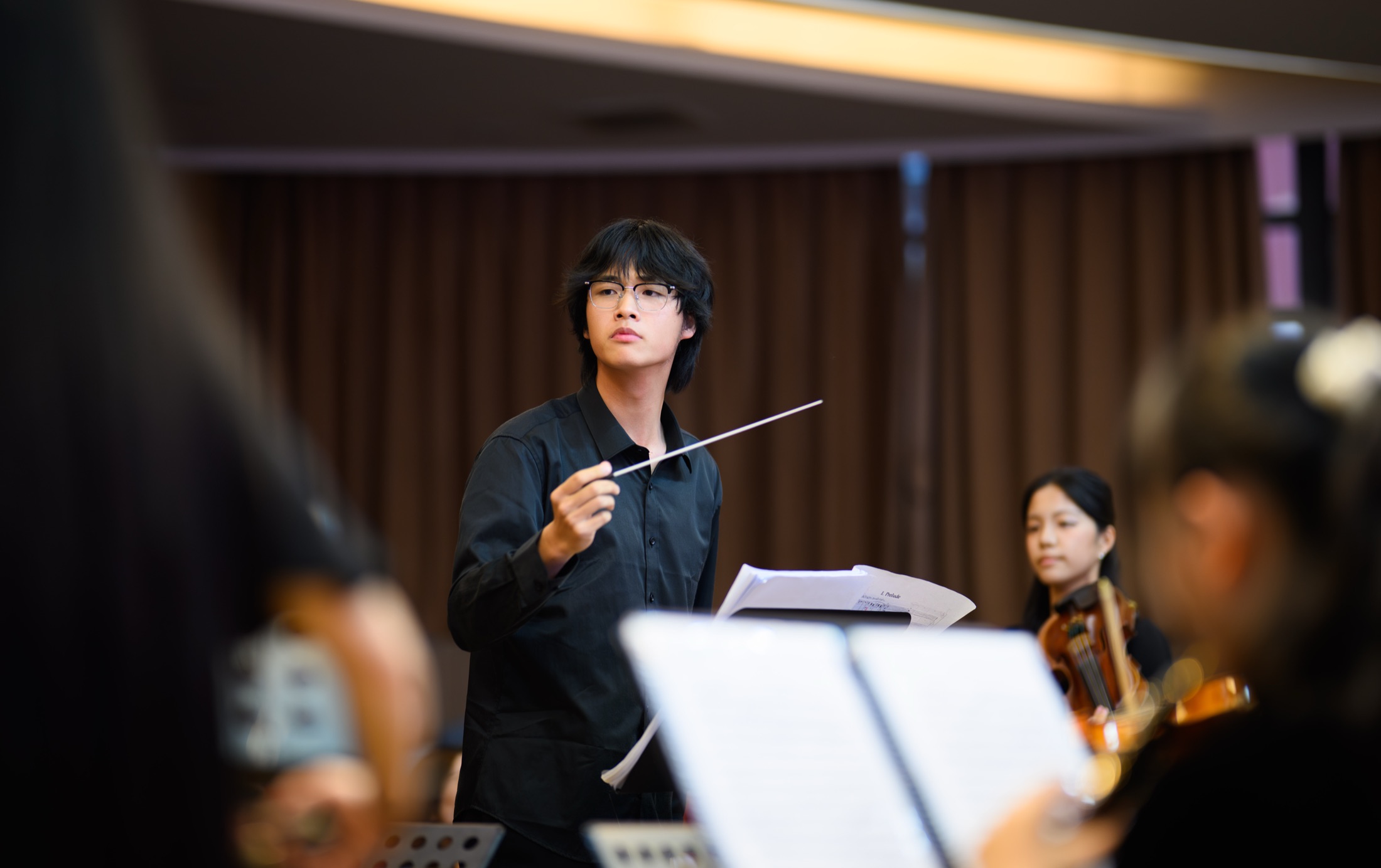 A conductor leading the school orchestra during an event